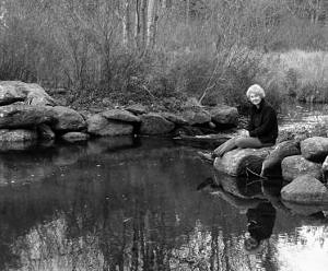 Jean Rosenthal sits by a beaver pond on her conserved land in Harrisville, NH. (photo © Eric Aldrich)
