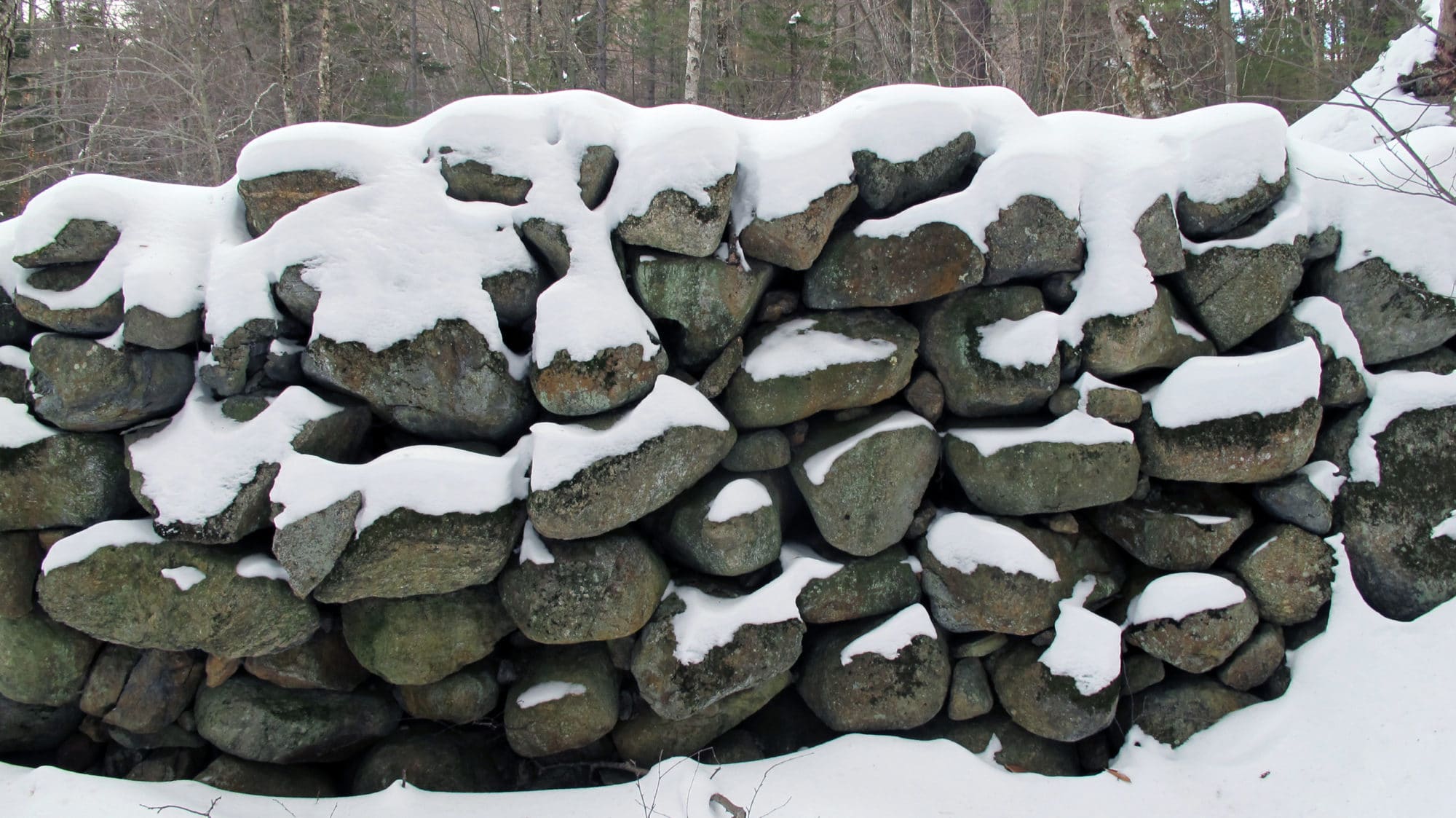 A stone wall, covered in snow.