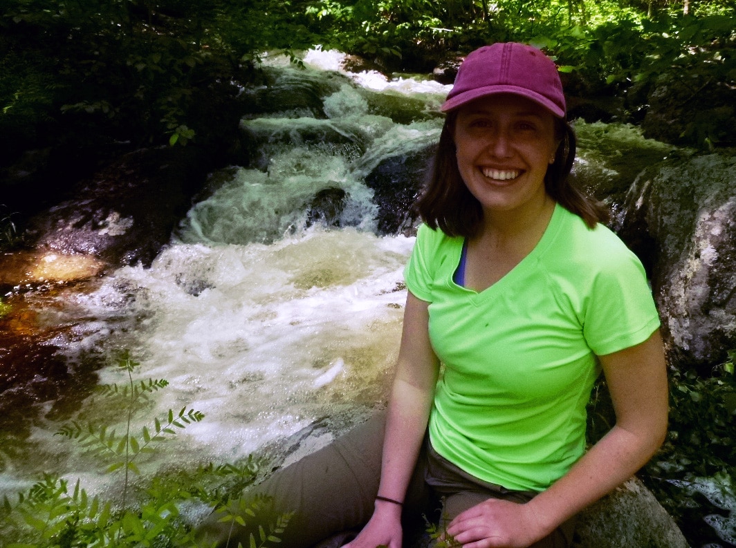 Courtney Dillon takes a hiking break next to a brook in spring flow.