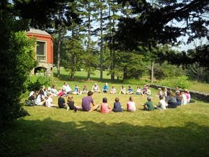 Campers sit in a circle on the Harris Center lawn.