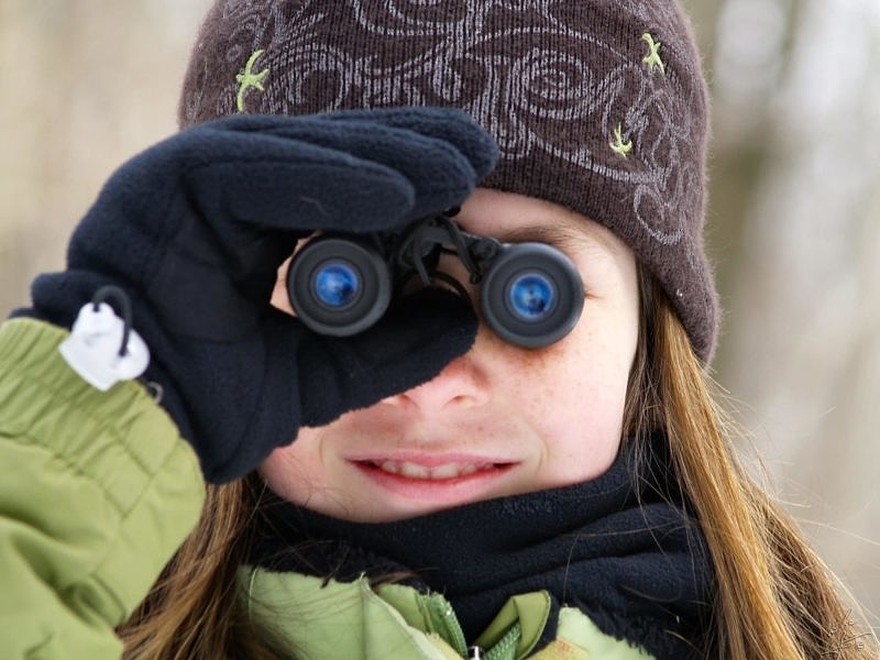 A young girl looks through binoculars. (photo © Eric Begin)