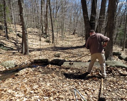 Eric Masterson clears a historic stone culvert of debris on the Harris Center's Cadot Trail. (photo © Meade Cadot)