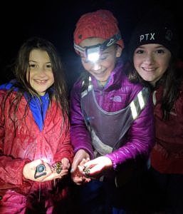 Three girls smile while holding spotted salamanders. (photo © Amy Unger)