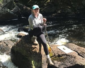 KSC Conservation Intern Lauren Peyser pauses on a boulder in the middle of a freshwater stream.