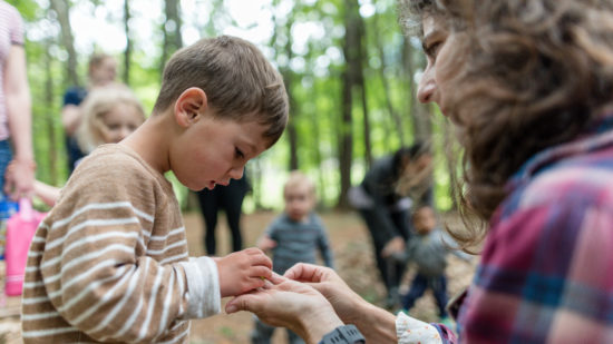 A young boy peers at something small held by Harris Center naturalist Susie Spikol. (photo © Ben Conant)