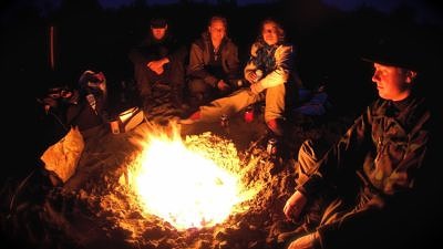 A group of people tells stories around a campfire. (photo © Ville Miettinen)