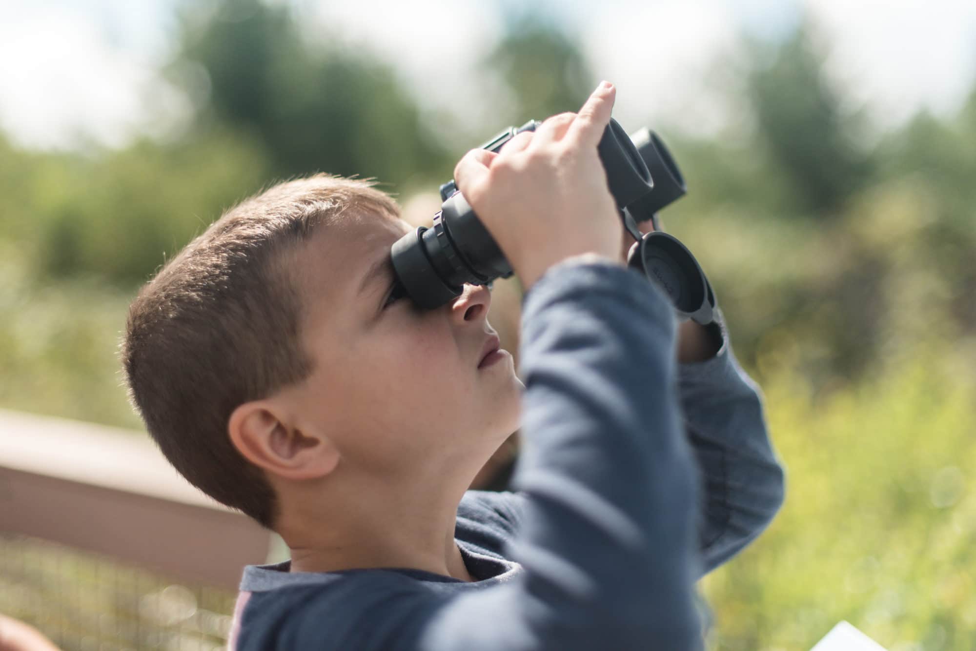 A boy peers through binoculars. (photo © Ben Conant)