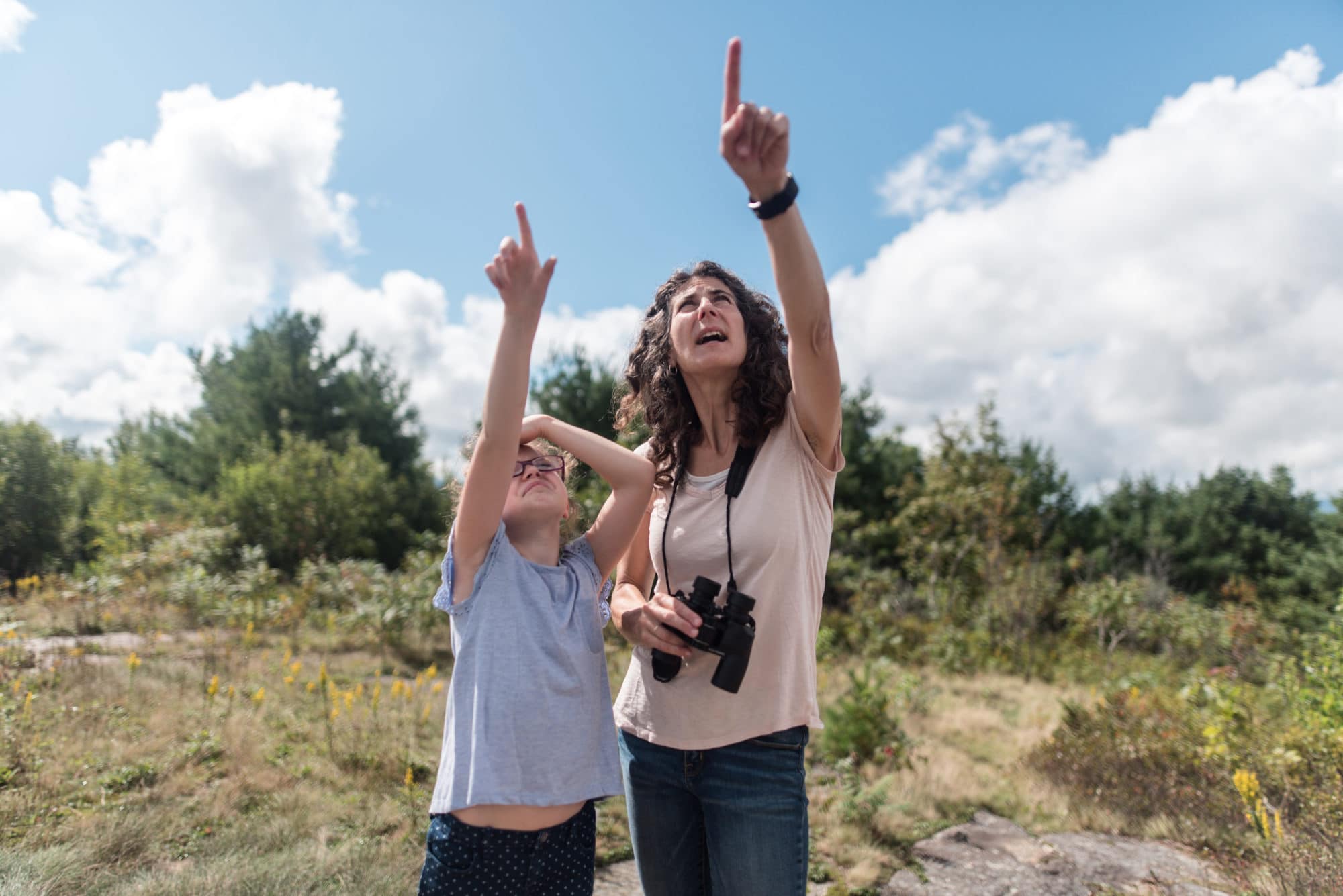 Harris Center teacher-naturalist Susie Spikol and a budding naturalist from Pierce Elementary School point to birds during a hawkwatching outing. (photo © Ben Conant)