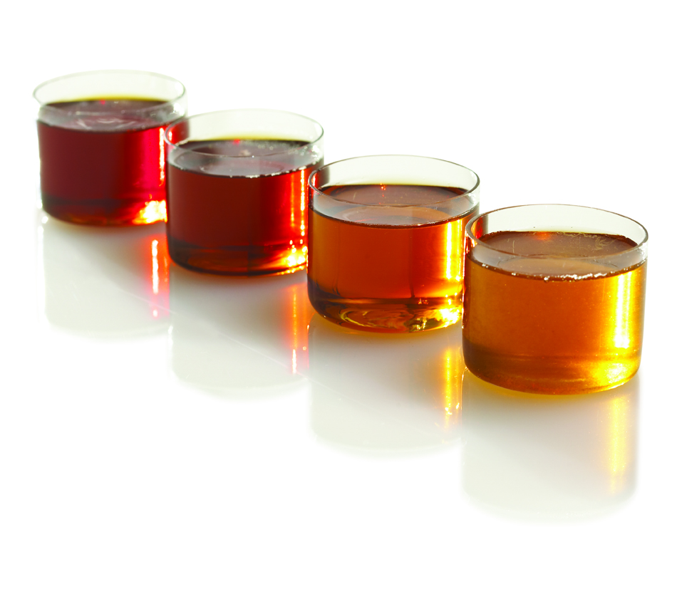 Four glass containers, each containing a different grade of maple syrup. (photo © protogarrett via the Flickr Creative Commons license)