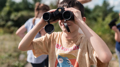 A boy peers through binoculars on a birding outing with the Harris Center. (photo © Ben Conant)