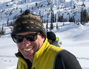 Michael George smiles on a snowy day in the mountains.