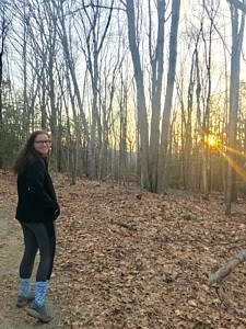 Katelyn Fournier watches the sun set through the woods.