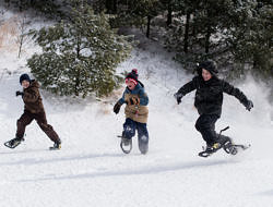 A group of boys run on snowshoes. (photo © Ben Conant)