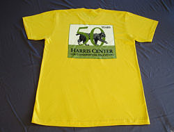 A photo of the Harris Center's 50th Anniversary commemorative tee shirt, in goldenrod.