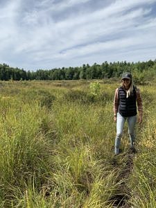 A photo of Jackie Lundsted walking through a wetland.