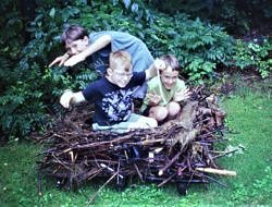 Summer campers sit in an oversized, handmade stick nest.
