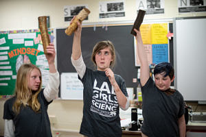 Middle school girls hold up pieces of wood during a LAB GIRLS session on forestry. (photo Ben Conant)
