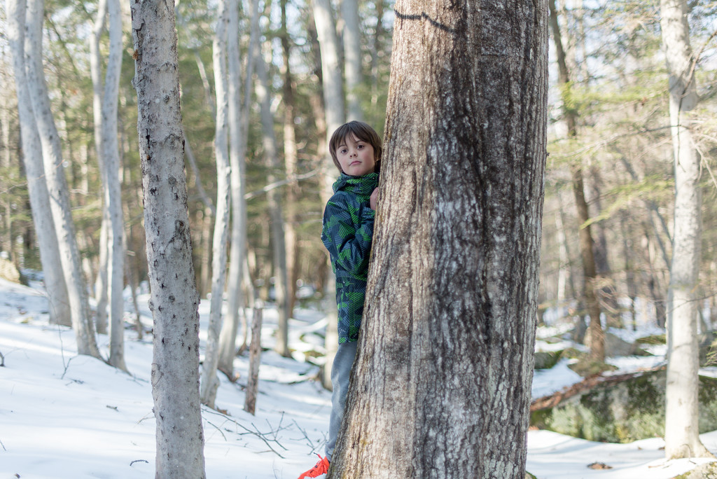 A child peaks out from behind a tree. (photo Ben Conant)