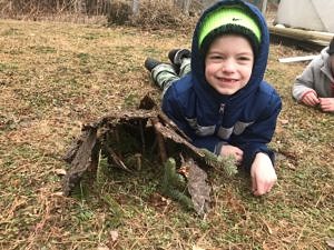 A kindergartener poses with the shelter he built for his stick person "peep." (photo © Jenna Spear)