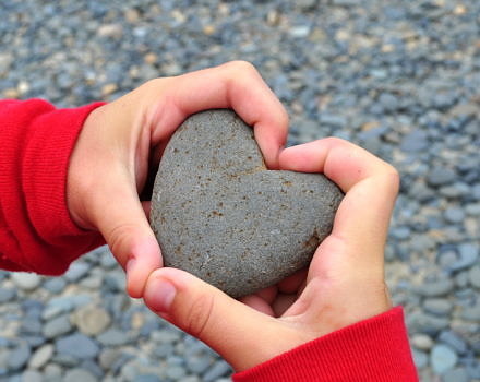 A child holds a heart-shaped stone. (photo © Lisa L Wiedmeier via the Flickr Creative Commons)