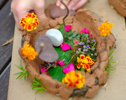 A kid making a fairy house out of clay and flowers. (photo © Howard County Library System via the Flickr Creative Commons)