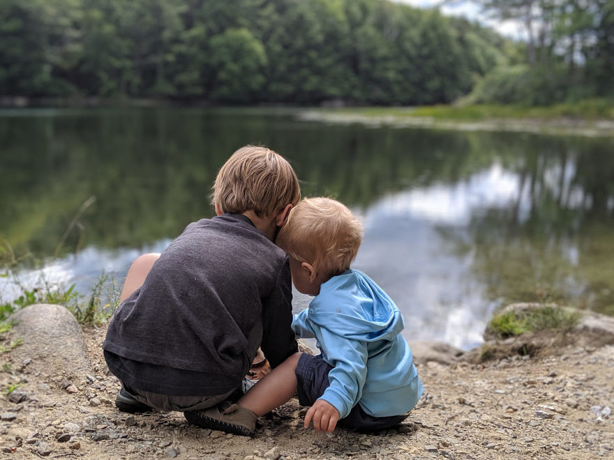 Two young children sit at the edge of Spoonwood Pond. (photo © Jill Griffiths)