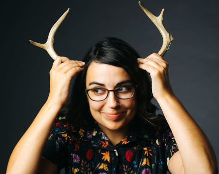 A photo of cartoonist Rosemary Mosco holding antlers up to her head. (photo © Rosemary Mosco)