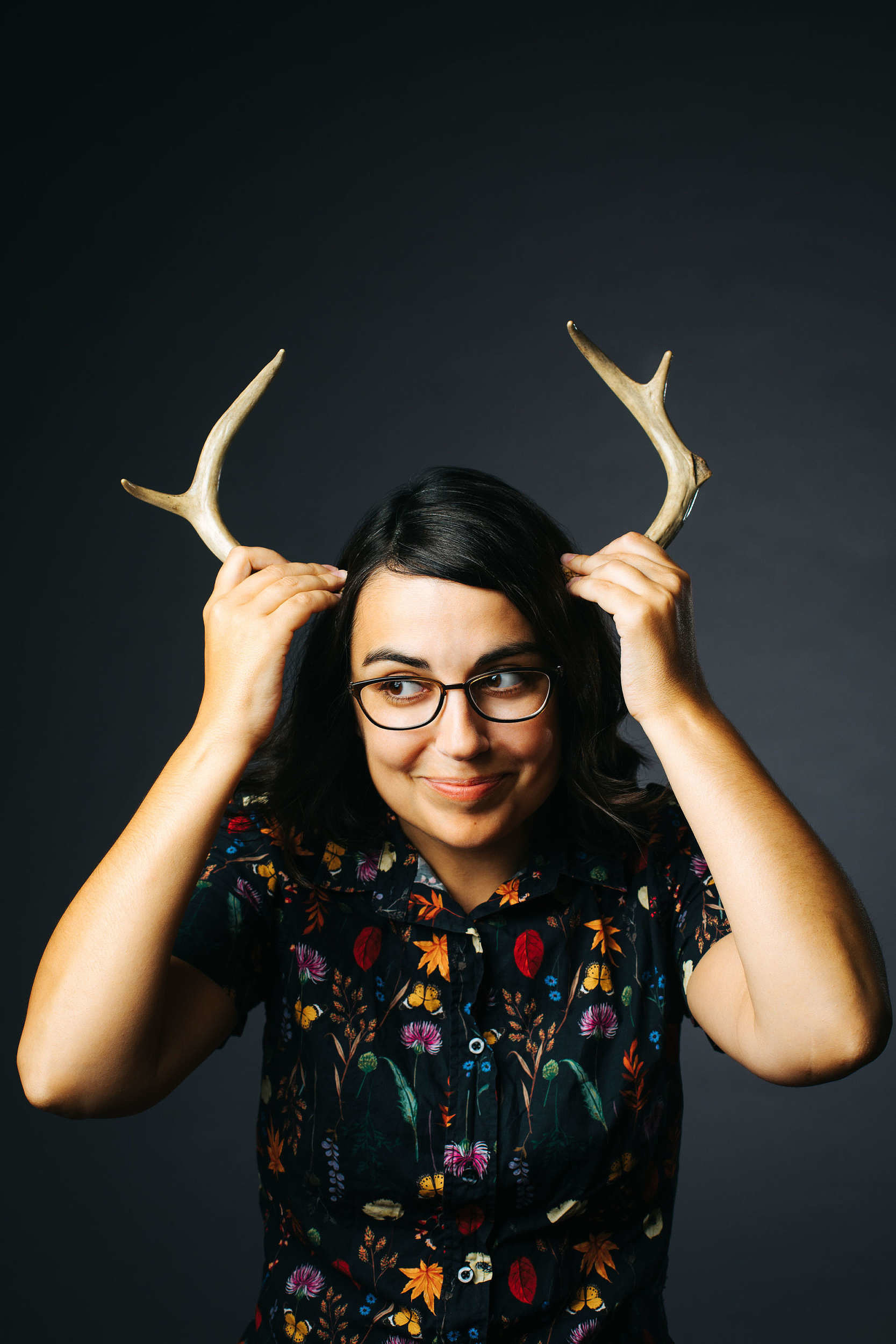 A photo of cartoonist Rosemary Mosco holding antlers up to her head. (photo © Rosemary Mosco)