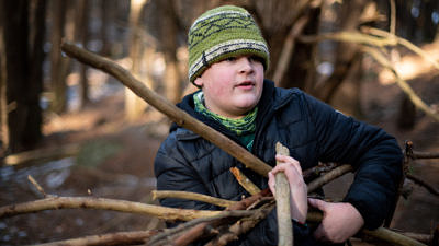 A middle school boy collects sticks to build a shelter. (photo © Ben Conant)
