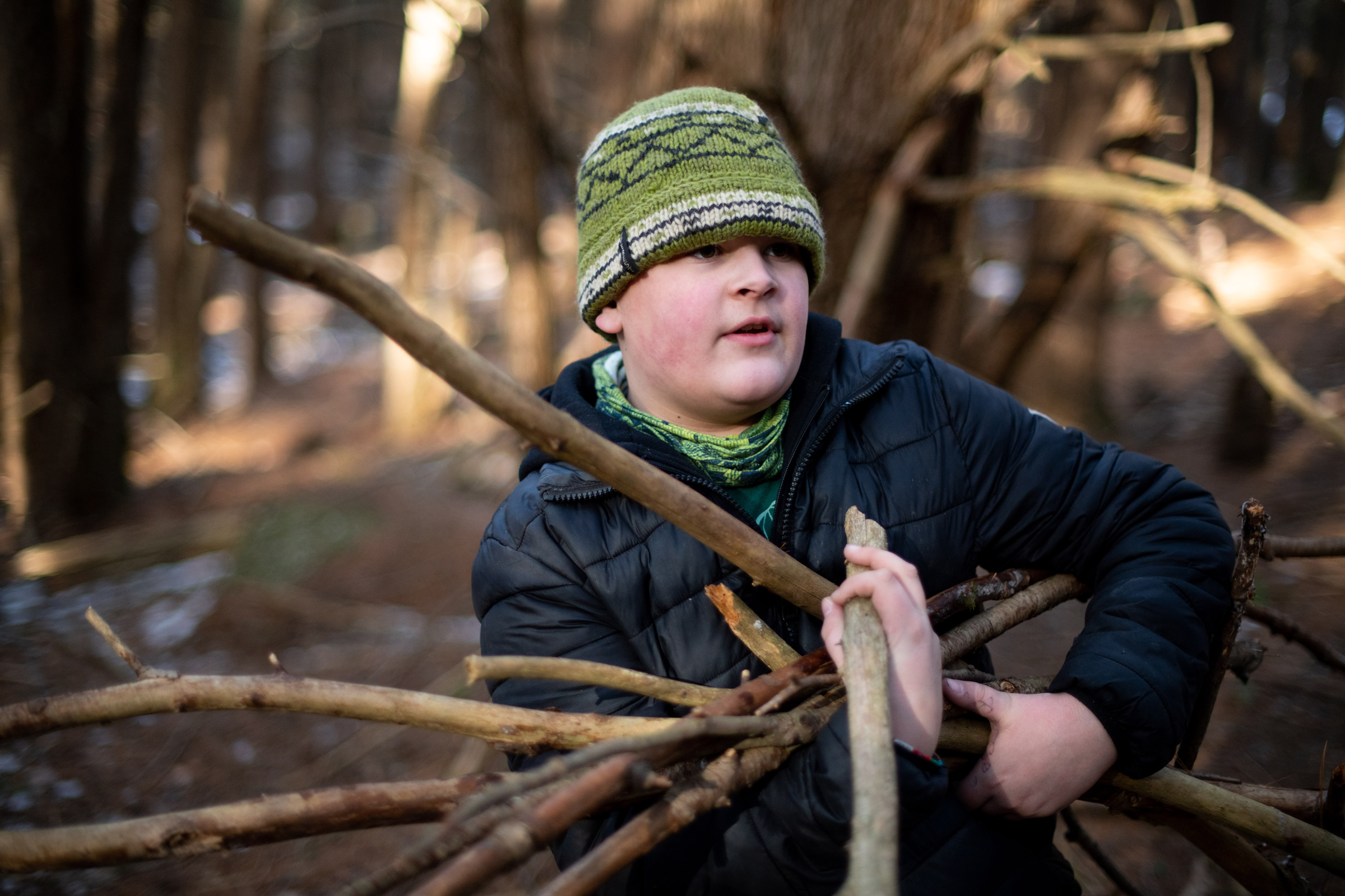 A middle school boy collects sticks to build a shelter. (photo © Ben Conant)