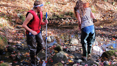 Two girls, wearing life vests and hip waders, stand in a woodland stream. (photo © Brett Amy Thelen)