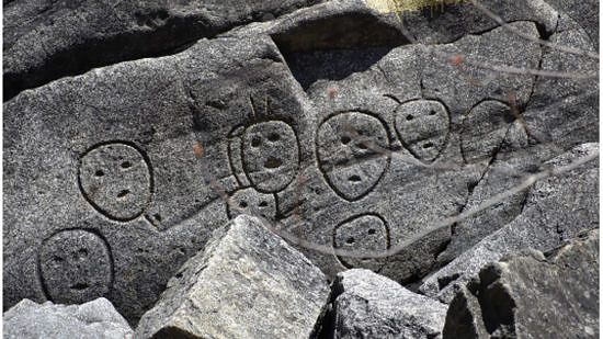 Petroglyph faces carved into gray stone. (photo © Bob Goodby)