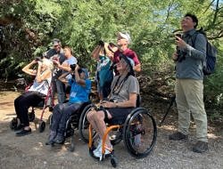 A group of people, some in wheelchairs, holding binoculars. (photo © Freya McGregor)