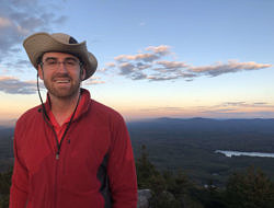 Ethan Harper-Lentricchia smiles on a mountain summit.