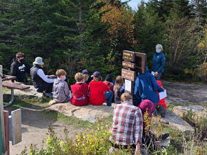 Harris Center volunteer Beth Corwin teaches a group of students about raptor migration at the Pack Monadnock Raptor Observatory.