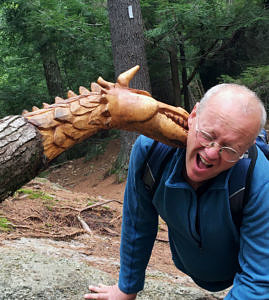 Eric Swope pretends to be bitten by a carved wooden dragon on the Harris Center's Harriskat Trail.