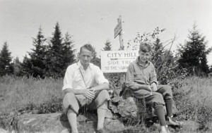 A black-and-white photo of two young men sitting on a boulder in front of a sign that says "City Hill." (photo courtesy of Rick Church)