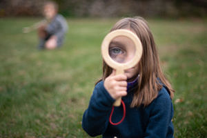 A girl uses a magnifying glass to look closely at an animal skull. (photo © Ben Conant)
