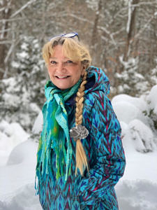 Sigrid-Scholz-Karabakakis, wearing a winter coat and with her long blond hair in a braid.
