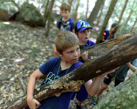 A group of boys works together to build a fort in the woods. (photo © Ben Conant)