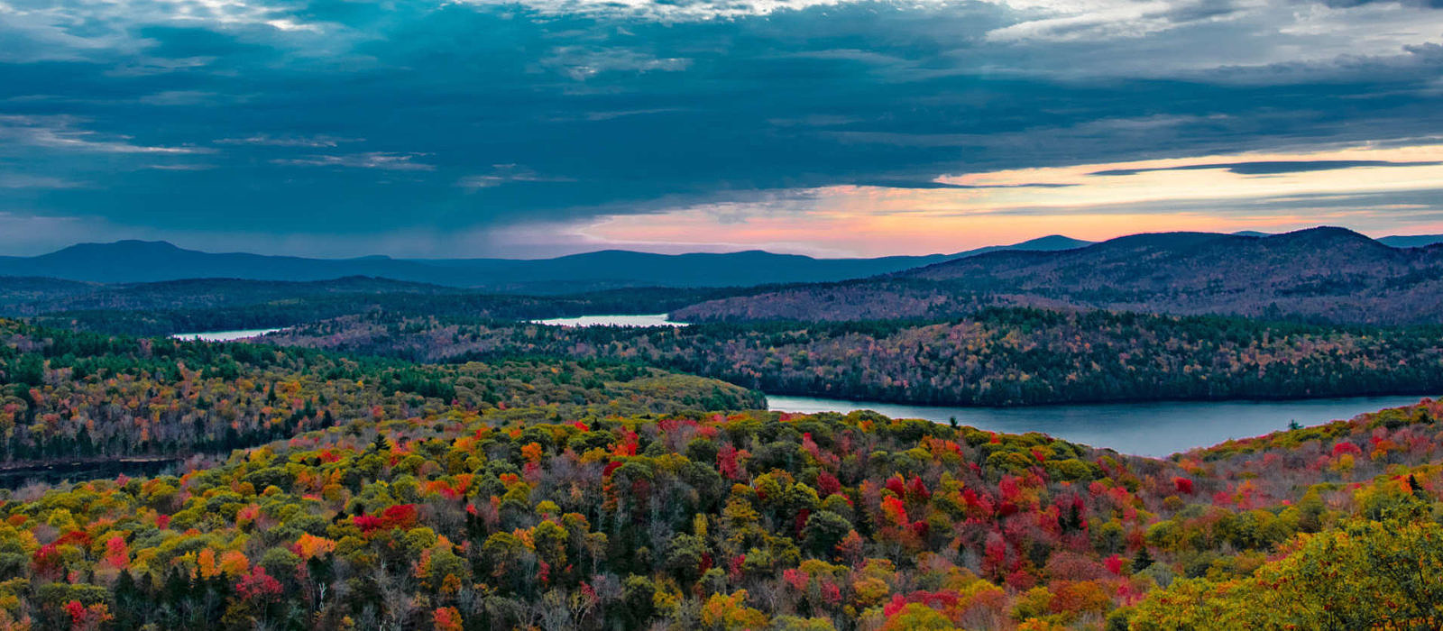 A panormaic view of Spoonwood Pond, Lake Nubanusit, and surrounding woods in brilliant fall color, as seen from the Kulish Ledges Trail. (photo © Will Kindler)