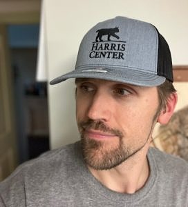 A man wearing a gray ball cap, with the Harris Center logo on it. The logo is embroidered in black.