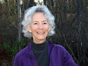 Sandy Bibace, smiling, as she stands in front of a wooded area.