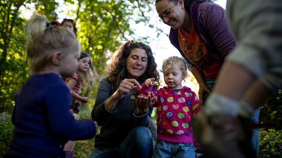Naturalist Susie Spikol points at something on her hand, while children and parent look on (photo: Ben Conant)