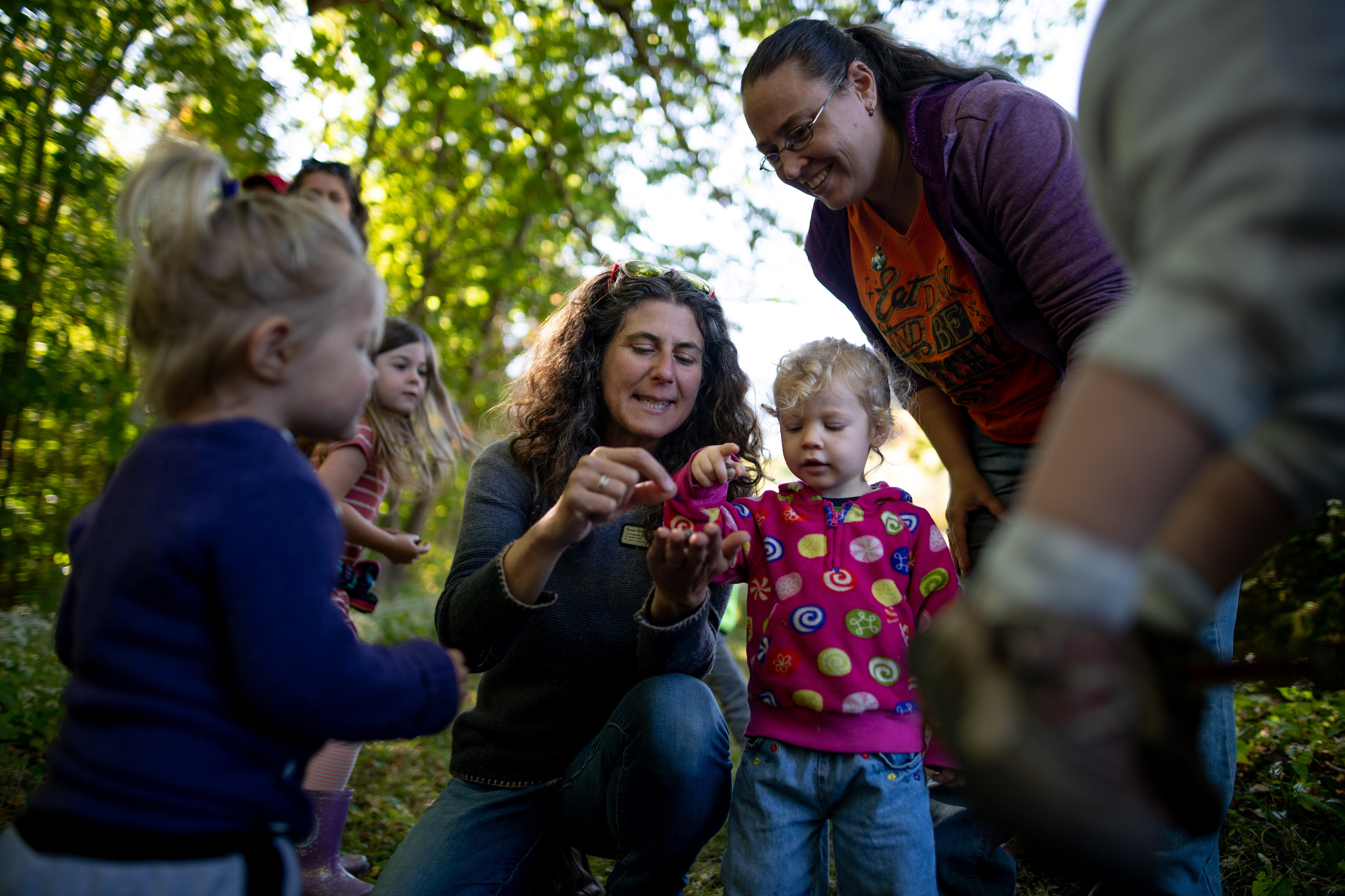 Naturalist Susie Spikol points at something on her hand, while children and parent look on (photo: Ben Conant)