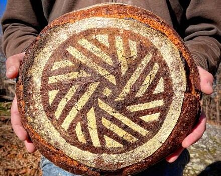 A loaf of bread with a geometric design, held up for the camera. (photo: Flagleaf Bakery)