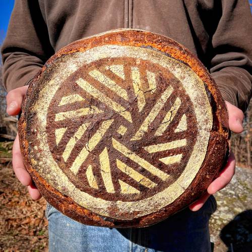 A loaf of bread with a geometric design, held up for the camera. (photo: Flagleaf Bakery)