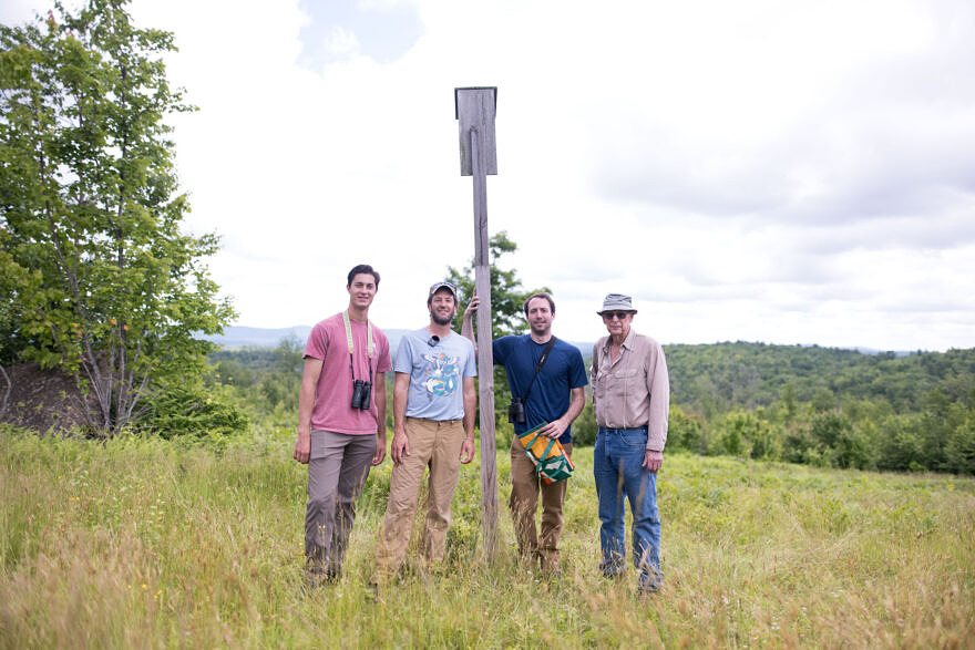 A group of four men smile with a kestrel nest box. (photo © Ben Conant)
