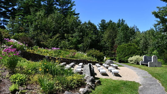 Flowers grow along a small slope, with rows of white benches between, next to a walking path. (photo © Audrey Dunn)