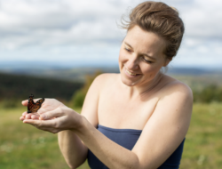 Jazimina Creamer-MacNeil holds a Monarch butterfly in her hands and smiles. (photo © Lori Pedrick)